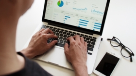 Person tippt auf einem Laptop mit einem Marketing-Dashboard auf dem Bildschirm