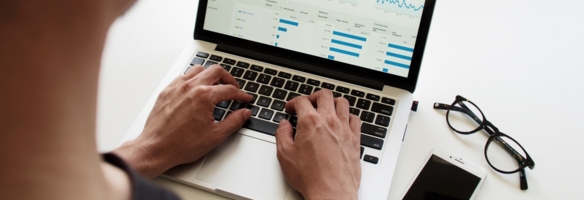 Person tippt auf einem Laptop mit einem Marketing-Dashboard auf dem Bildschirm