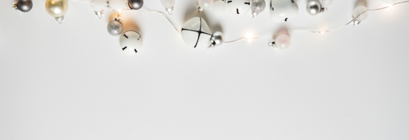 Lichterkette und stilisierter Weihnachtsschmuck auf hellem Hintergrund