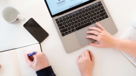 Impression eines Arbeitsplatzes in Vogelperspektive mit Laptop, Notizbuch