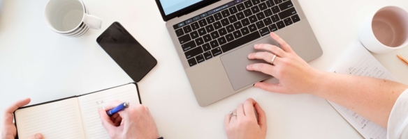 Impression eines Arbeitsplatzes in Vogelperspektive mit Laptop, Notizbuch