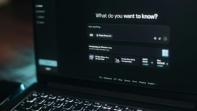 Laptop-Bildschirm mit der Perplexity-AI-Suchoberfläche im Dunkelmodus und der Frage „What do you want to know?"