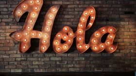 Beleuchtetes Vintage-Schriftzug-Schild mit dem Wort Hola auf einer Backsteinwand