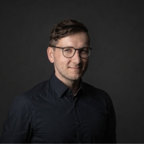 Man mit Brille und schwarzen Hemd.