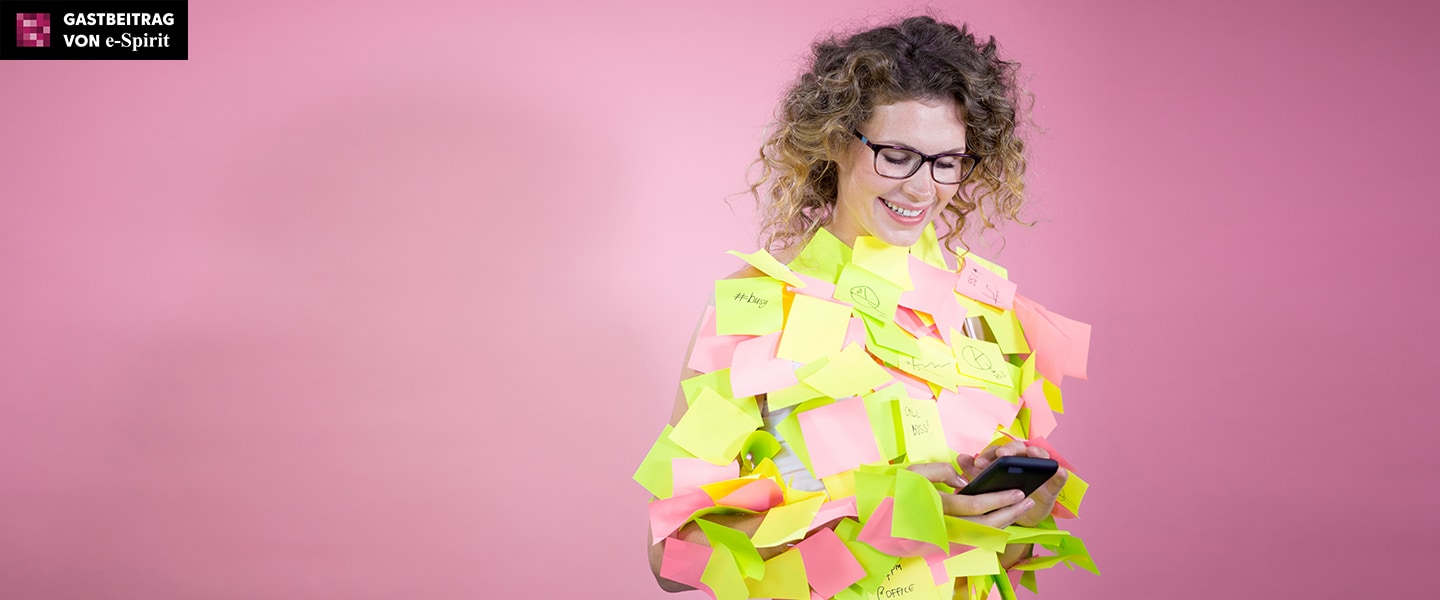 Frau schaut auf Handydisplay. Sie ist übersäht mit Post-it Klebezetteln.