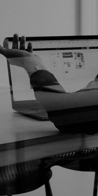 Schwarz-Weiß-Foto eines Entwicklers an zwei Laptops in einer dunklen Umgebung