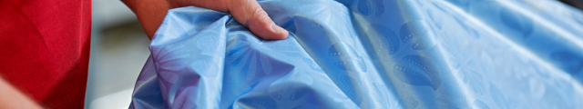 Nahaufnahme einer Hand, die einen glänzenden blauen Getzner Textil Stoff berührt