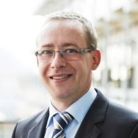 Man mit Brille und blauen Sakko, Hemd und Krawatte