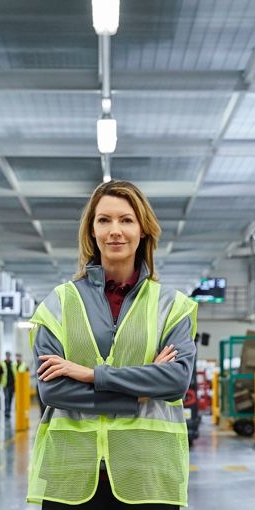Werksmitarbeiterin stehend in Fertigungsanlage