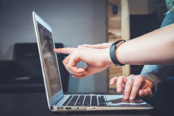 Eine Person zeigt mit dem Finger auf einen Laptop.