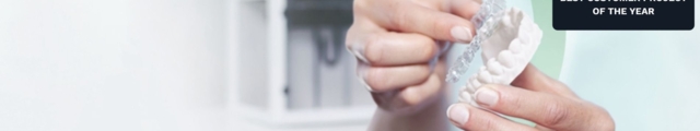 Nahaufnahme von Händen, die ein Zahnarzt-Modell und eine Dentalschiene halten, mit dem Ibexa Award-Badge „Best Customer Project of the Year 2024" oben rechts